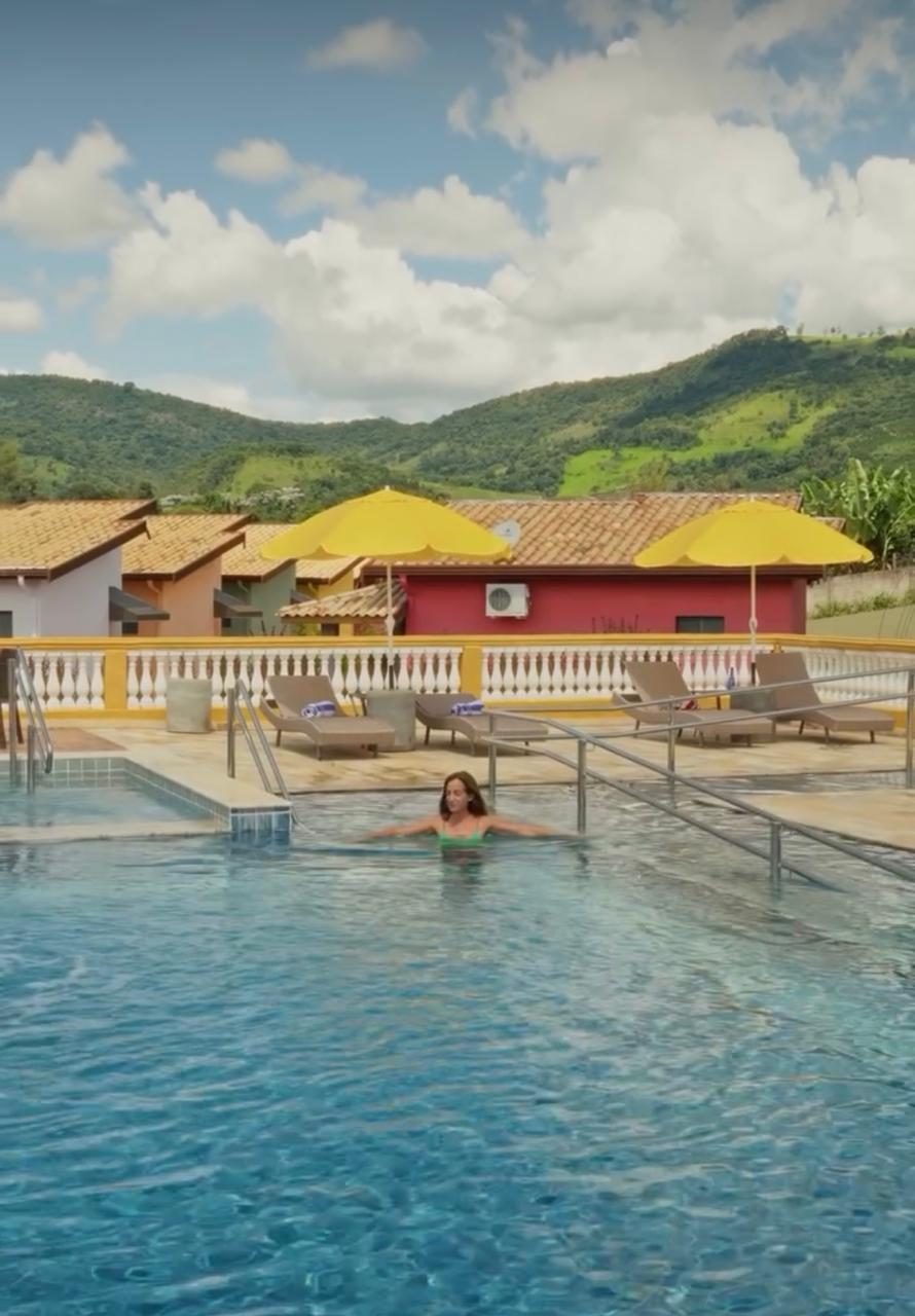 Piscina com guarda-sóis amarelos e vista para as montanhas de Serra Negra