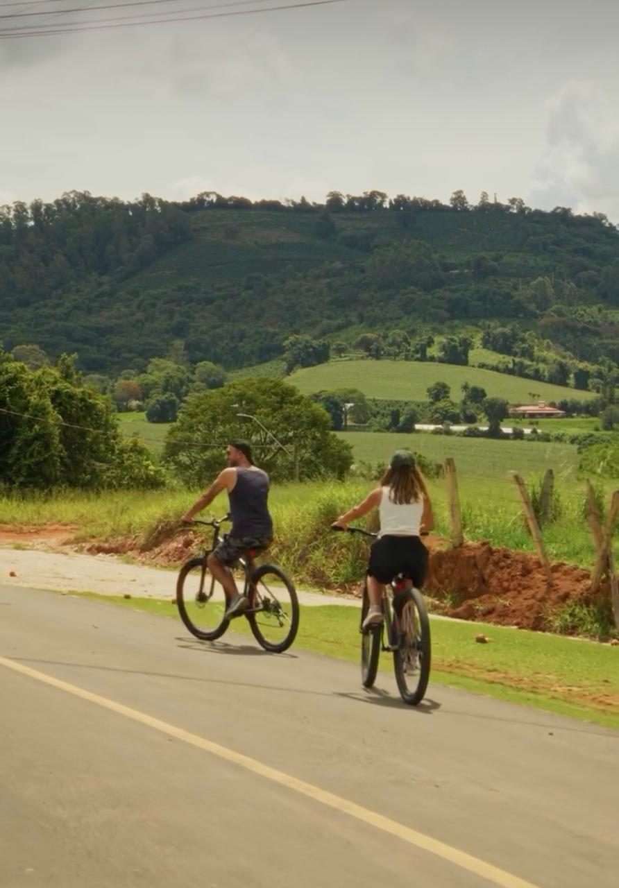 Casal pedalando pela estrada rural em meio à natureza