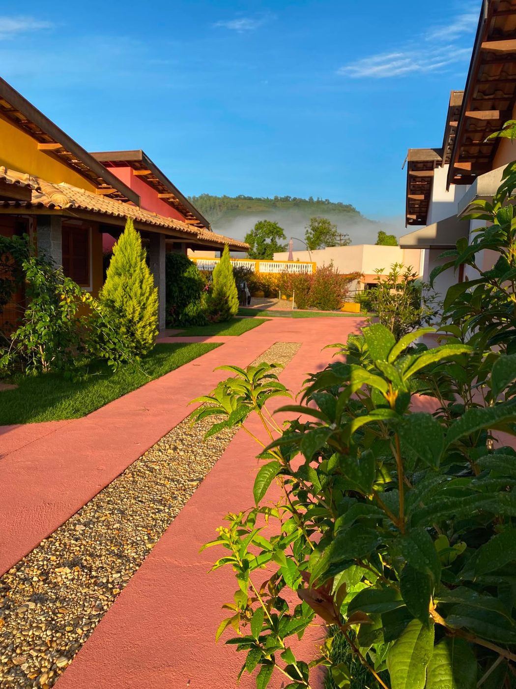 Caminho entre os chalés coloridos com jardins e montanhas ao fundo